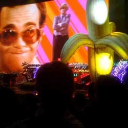 Photo of Elton John - The Red Piano - Las Vegas, NV, United States. Note the big screen, neon signs and blow up banana.